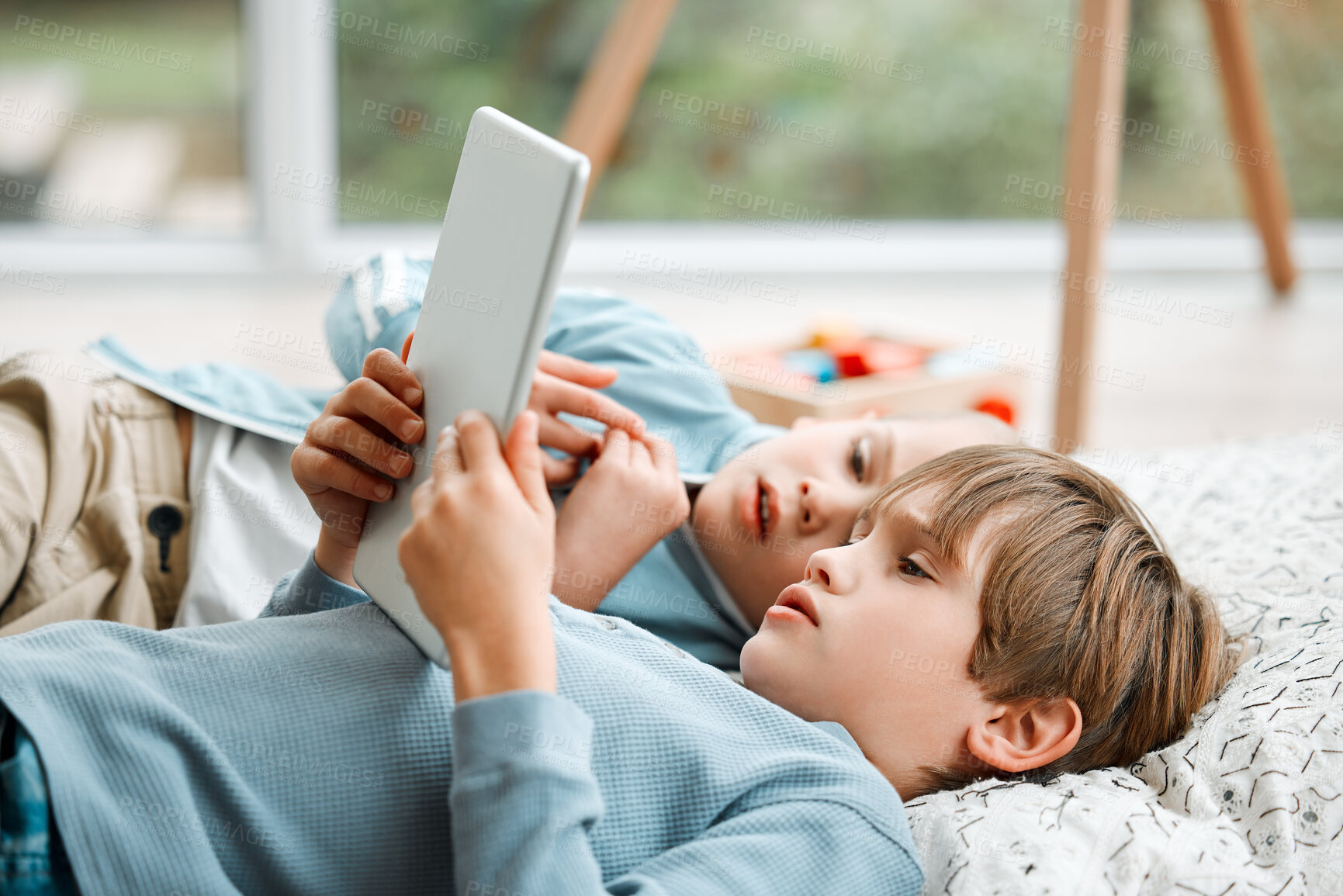 Buy stock photo Shot of two brothers using a tablet at home