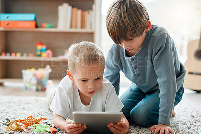 Buy stock photo Shot of two brothers using a tablet at home