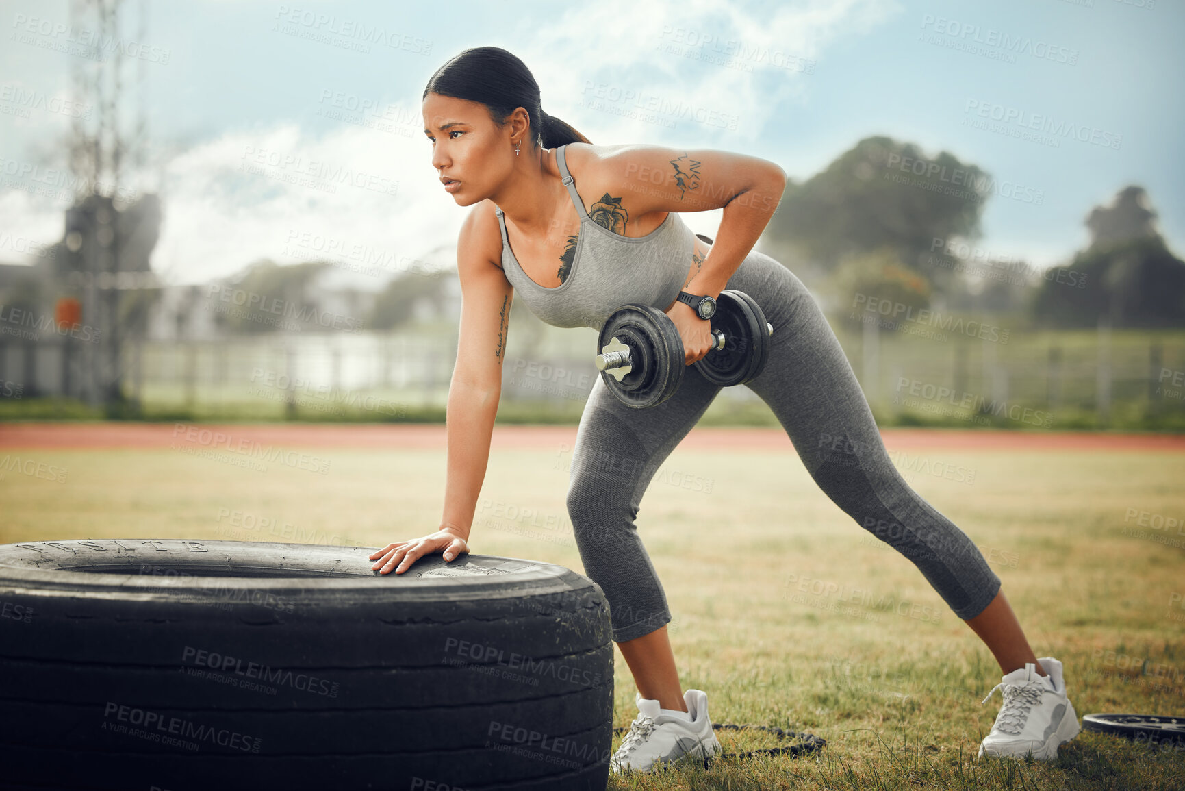 Buy stock photo Full length shot of an attractive young female athlete exercising with dumbbells outdoors