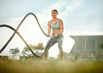 Buy stock photo Full length shot of an attractive young female athlete exercising with battle ropes outside