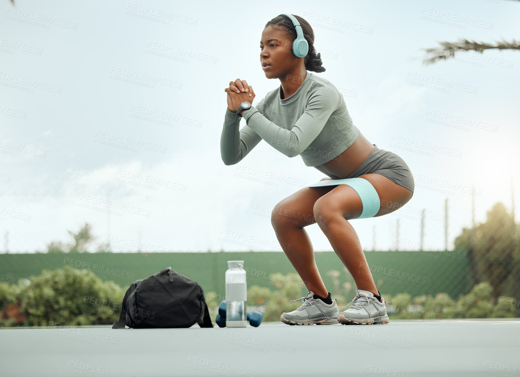 Buy stock photo Full length shot of an attractive young female athlete doing squats as part of her workout on a sports court