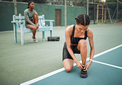 Buy stock photo Full length shot of an attractive young female athlete tying her laces during an outdoor workout with a friend in the background