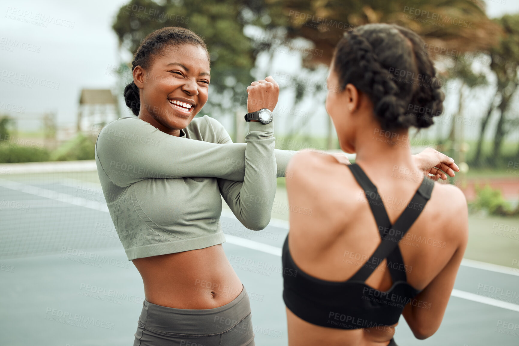 Buy stock photo Cropped shot of two attractive young female athletes warming up outside before beginning their workout