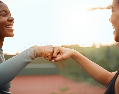 Buy stock photo Cropped shot of two attractive young female athletes fist bumping while exercising outside on a sports court