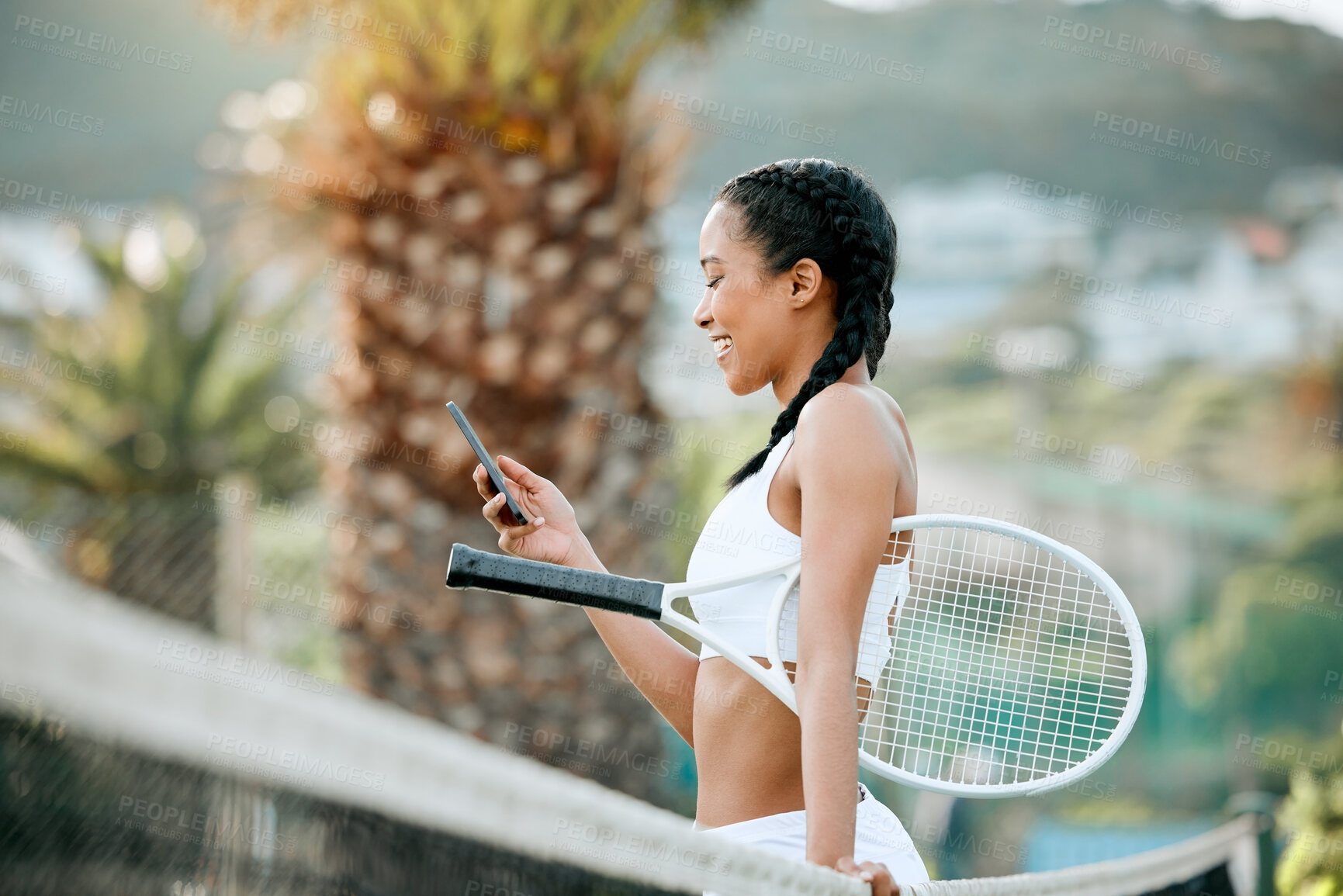 Buy stock photo Shot of a sporty young woman using a cellphone while playing tennis on a court