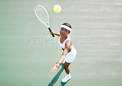Buy stock photo Shot of a young woman serving a ball while playing tennis on a court