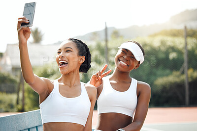 Buy stock photo Shot of two sporty young women taking selfies together on a tennis court