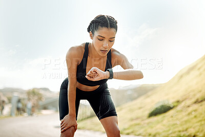 Buy stock photo Shot of a young woman taking a break during a run to check her watch