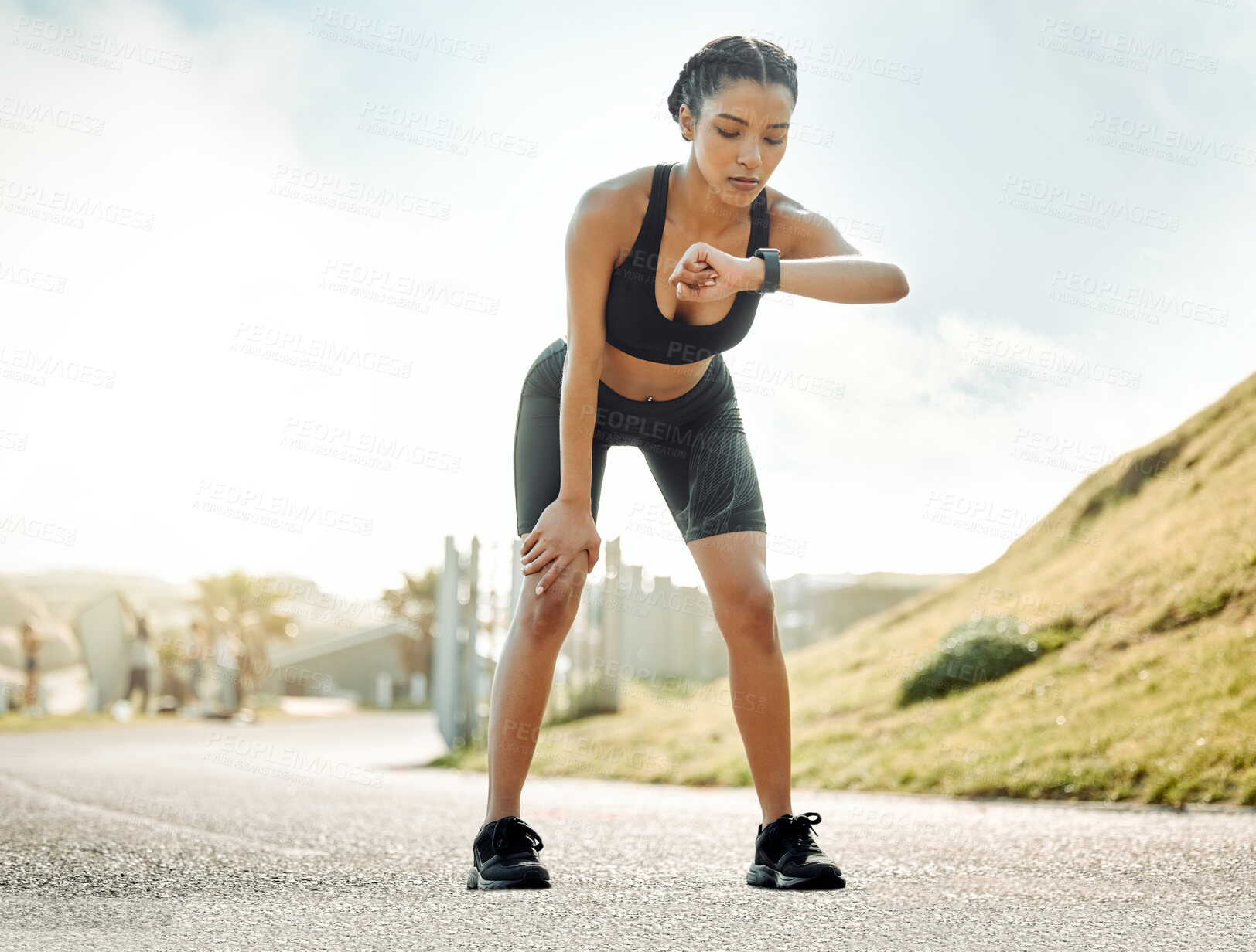 Buy stock photo Shot of a young woman taking a break during a run to check her watch