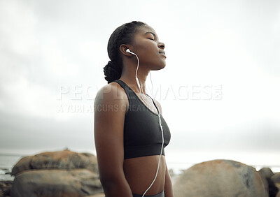 Buy stock photo Shot of a young woman listening to music during a workout