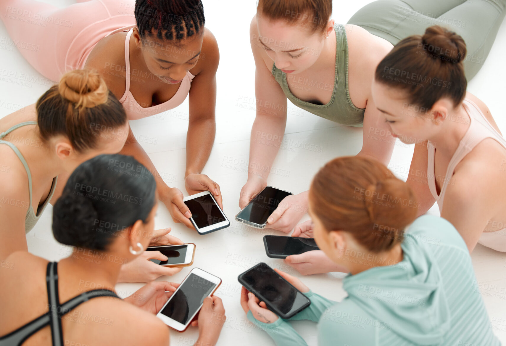Buy stock photo Shot of a fitness group using their cellphones while in a circle
