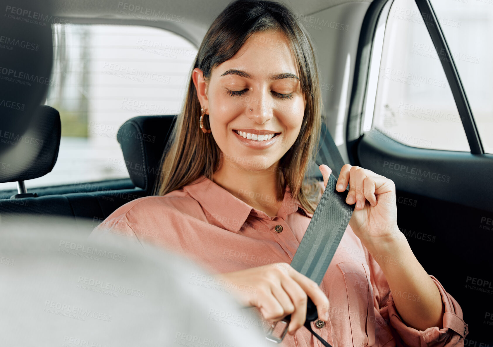 Buy stock photo Shot of a young woman fastening her seatbelt in a car