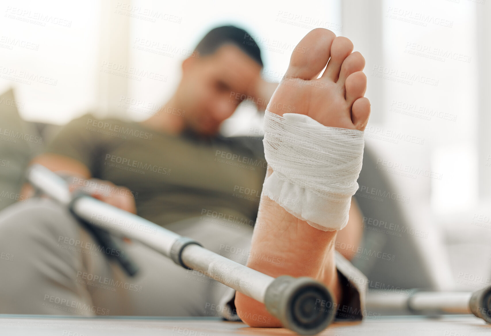 Buy stock photo Home, broken and man with injury, foot and bandage with crutch, comfort and inflammation. Person, apartment and closeup with guy, bruise and sprain with agony, ache and medical problem in lounge