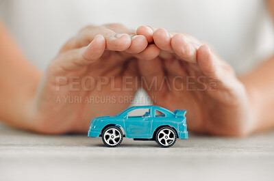 Buy stock photo Shot of a unrecognizable female covering a toy car with his hands at home