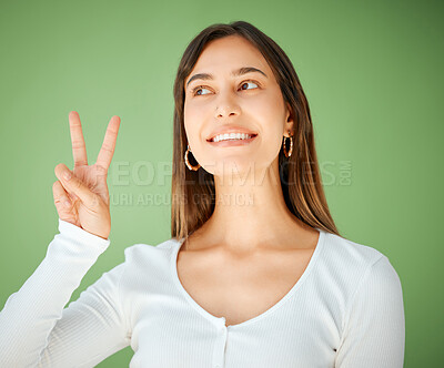 Buy stock photo Studio shot of a young woman showing the peace sign against a green background