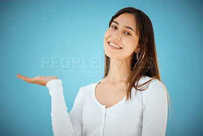 Buy stock photo Studio shot of a young woman holding her hand out against a blue background