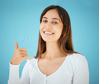 Buy stock photo Studio shot of a young woman holding her hand out and showing the hang ten sign