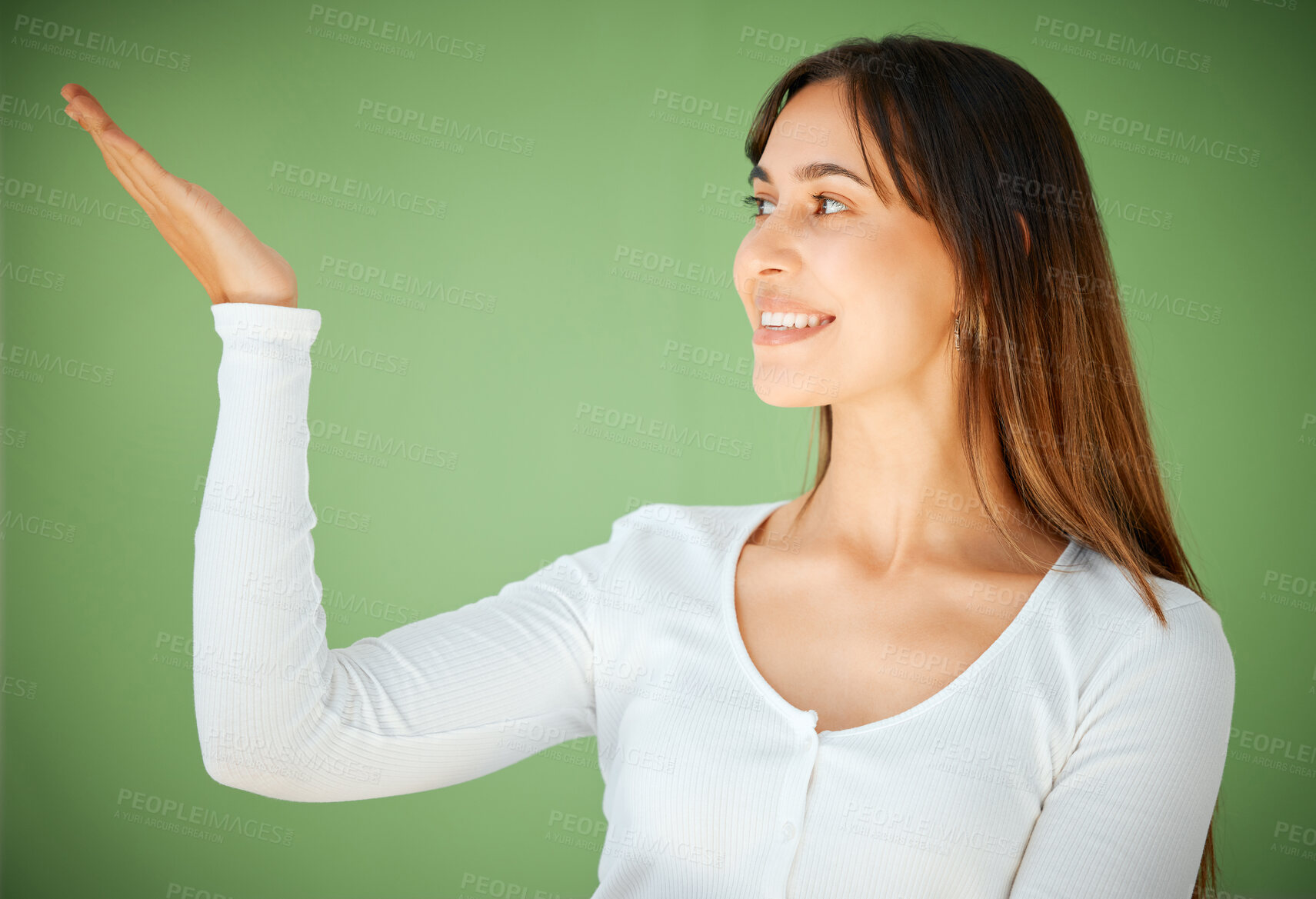 Buy stock photo Studio shot of a young woman holding her hand out against a green background