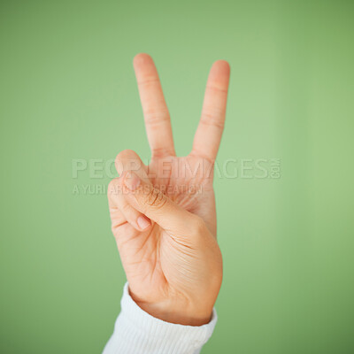Buy stock photo Shot of an unrecognizable woman showing the peace sign against a green background