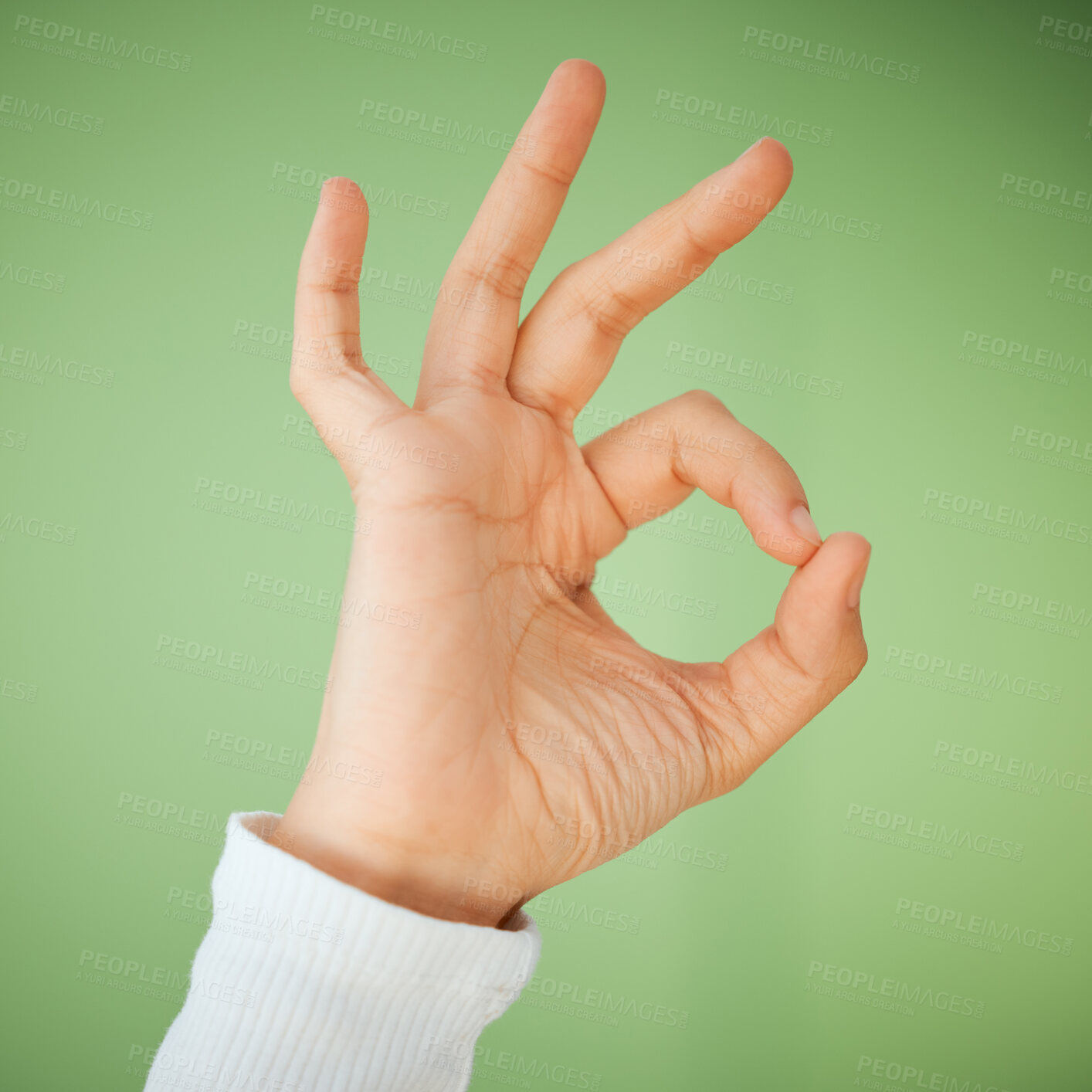 Buy stock photo Shot of an unrecognizable woman showing the OK sign against a green background