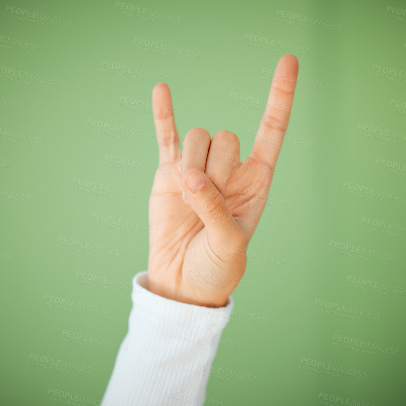 Buy stock photo Hand, rock and roll sign and studio on green background for music, peace and concert celebration. Person, finger and isolated with devil horn gesture or punk symbol for rebellion and grunge as rocker