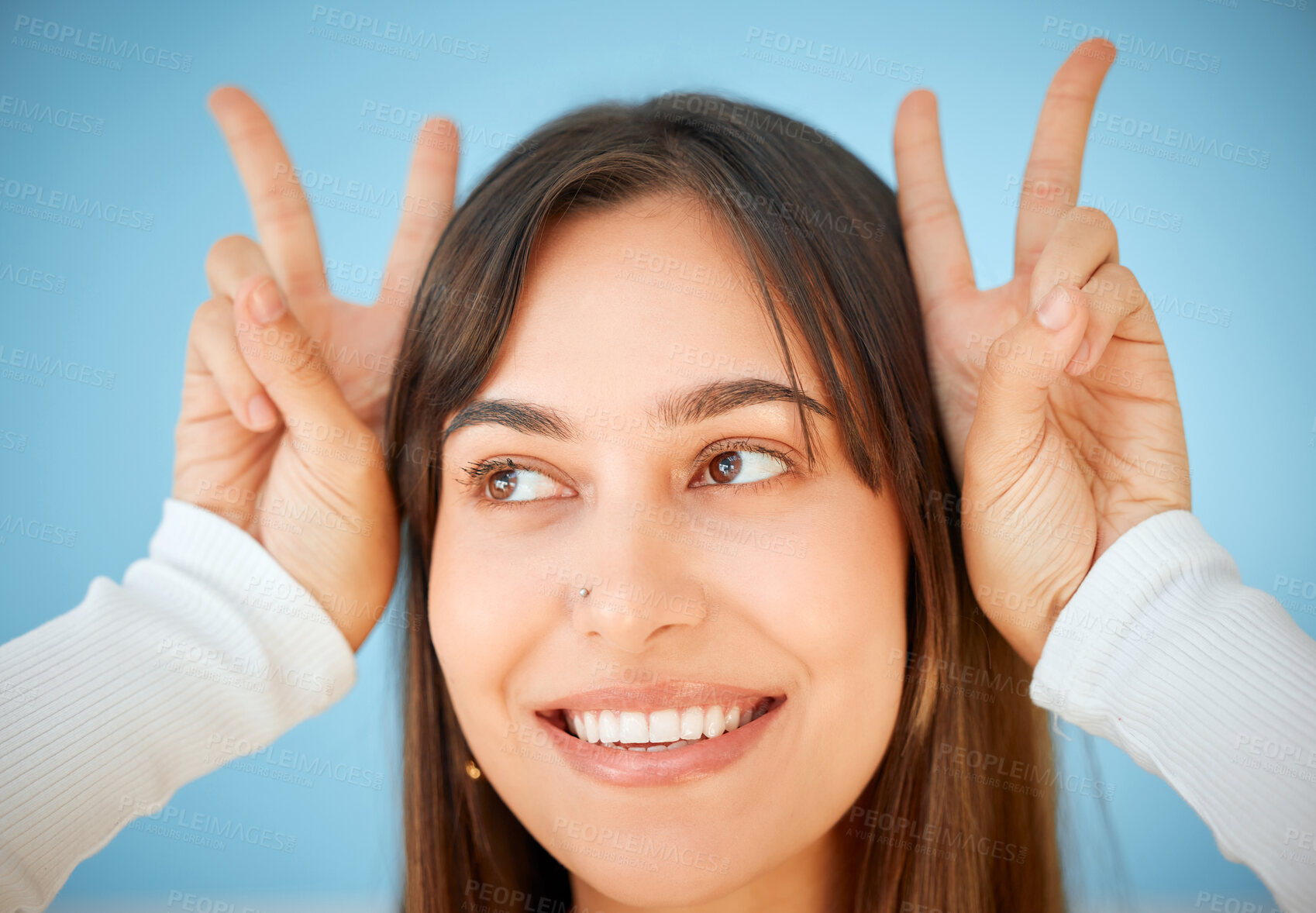 Buy stock photo Studio shot of a young woman showing the peace sign against a blue background