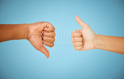 Buy stock photo Shot of unrecognizable people showing the thumbs up and thumbs down against a blue background