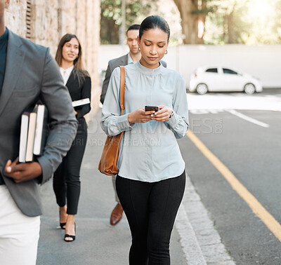 Buy stock photo Shot of a businesswoman using her smartphone to send a text while walking