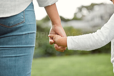 Buy stock photo Shot of a little girl holding her mother’s hand while going for a walk in the park