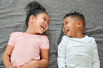 Buy stock photo Shot of two young siblings lying on the floor together at home