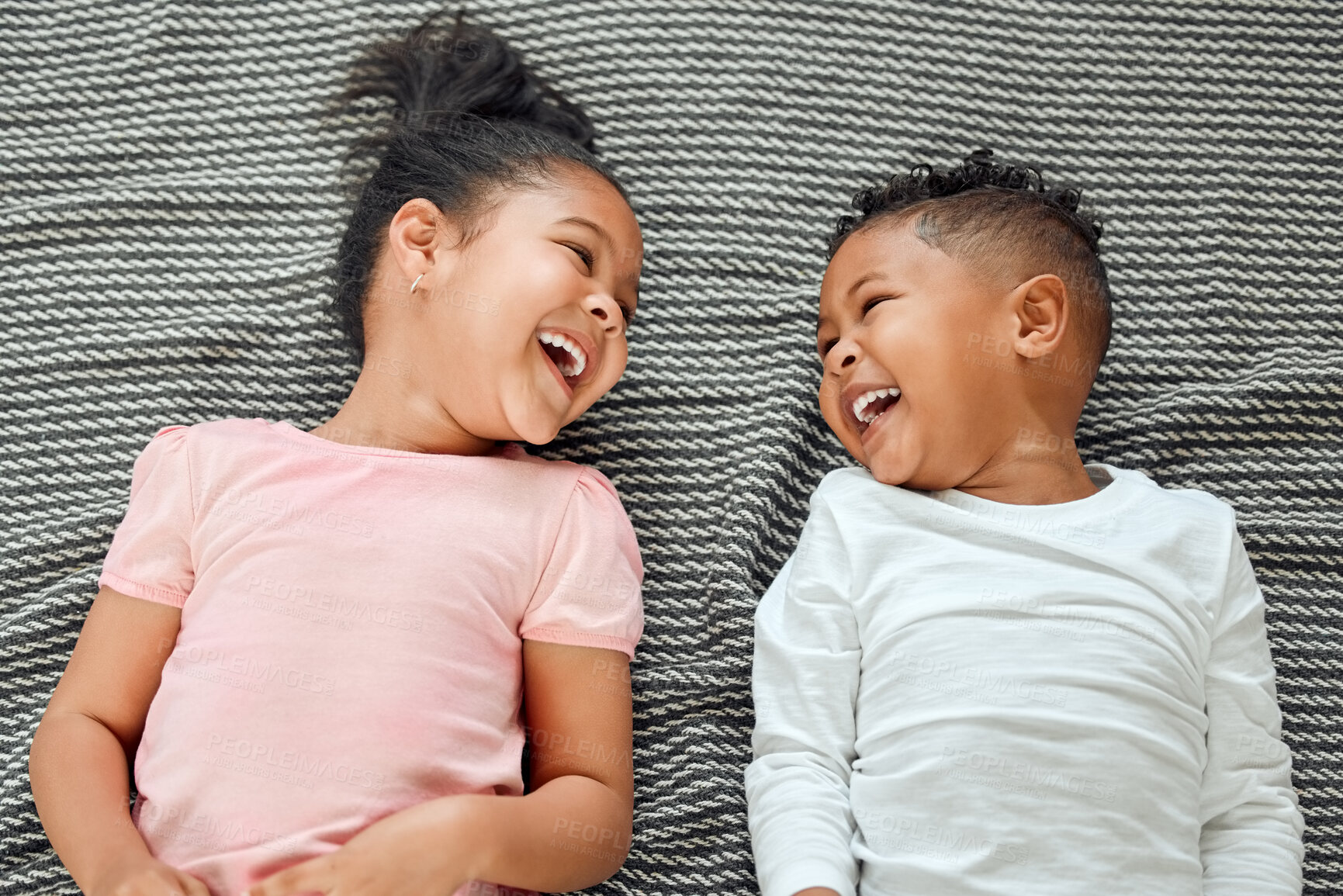 Buy stock photo Top view, siblings and laughing on bed together, happiness and funny conversation for bonding in home. Above, children and bedroom for silly humor in communication, brother and sister for family love