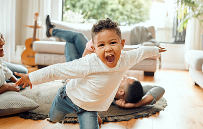 Buy stock photo Portrait of an adorable little boy opening his arms while his family bonds on the lounge floor in the background