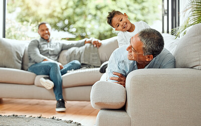 Buy stock photo Shot of an older man bonding with his son while playing with his grandson on the sofa