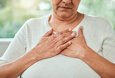 Buy stock photo Shot of an unrecognizable woman experiencing chest pain while sitting on the sofa alone
