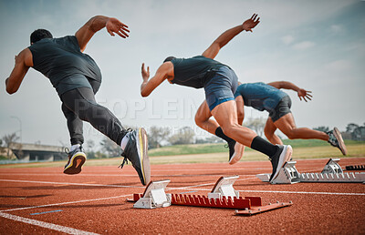 Buy stock photo Rearview shot of three unrecognizable young male athletes starting their race on a track