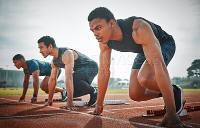 Buy stock photo Full length shot of three handsome young male athletes starting their race on a track