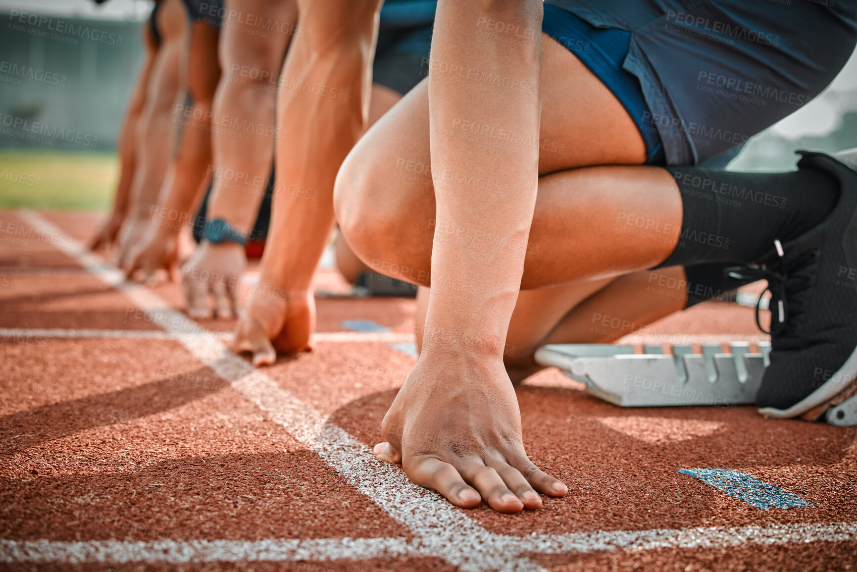 Buy stock photo Cropped shot of three unrecognizable male athletes starting their race on a track