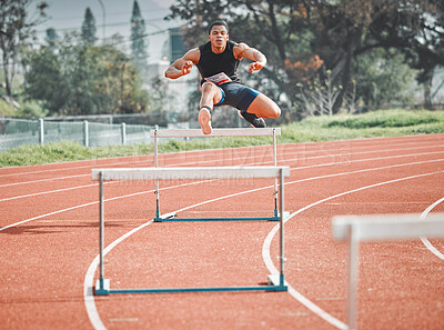 Buy stock photo Full length shot of a handsome young male athlete practicing hurdles on an outdoor track