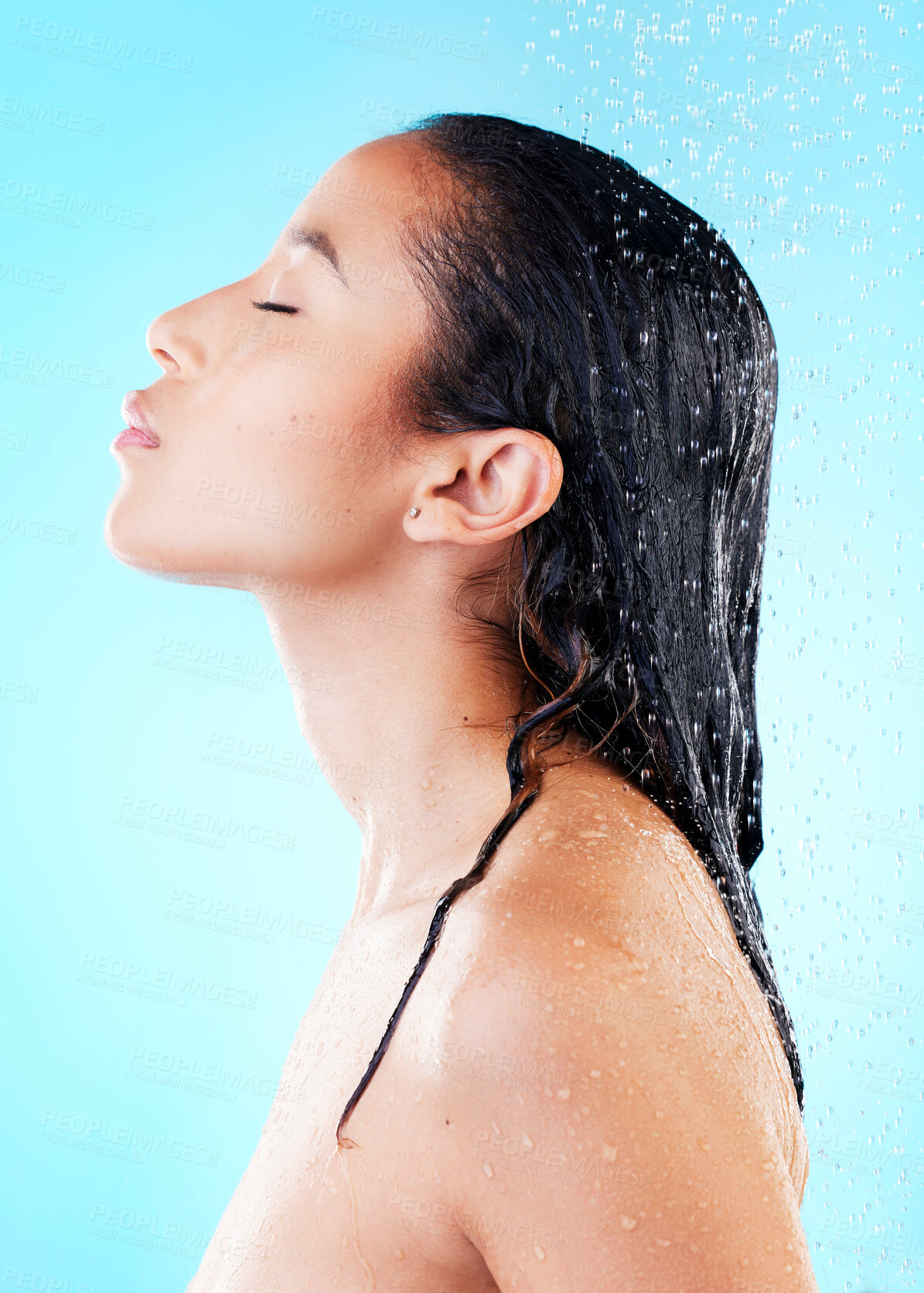 Buy stock photo Woman, washing hair or showering in blue studio background for cosmetics, hygiene and wellness, Female person, eyes closed and water cleaning head for grooming, skincare and treatment or bath