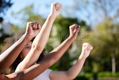 Buy stock photo Shot of an unrecognisable group of women raising their hands in strength outside