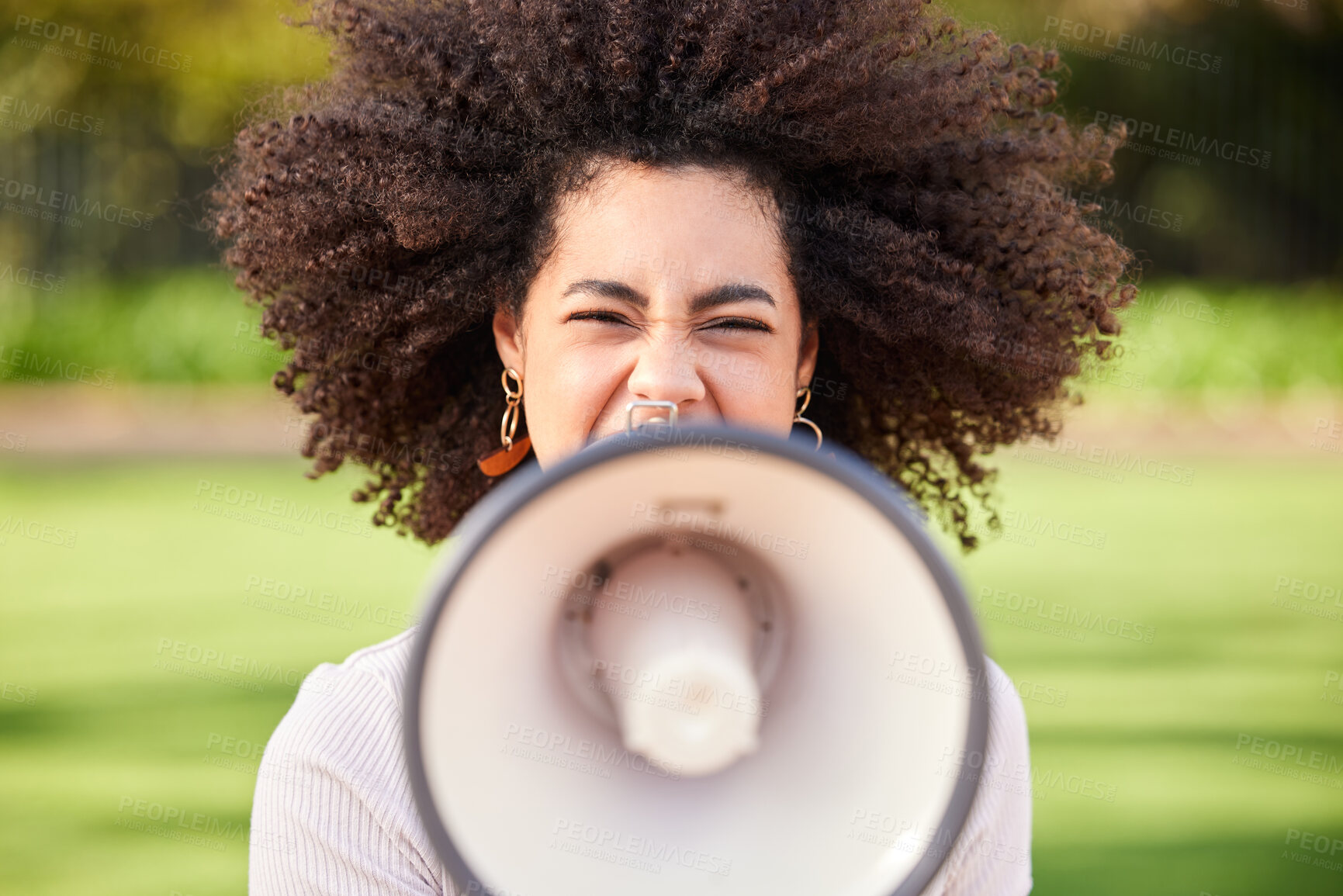 Buy stock photo Shot of a young woman screaming into a loudspeaker while protesting in the park