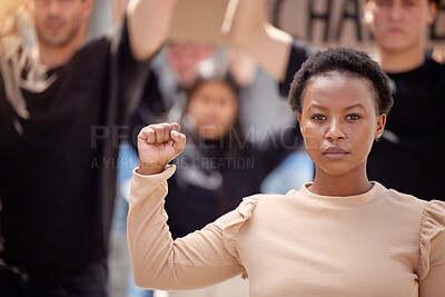 Buy stock photo Shot of a young woman with her fist raised in solidarity at a march