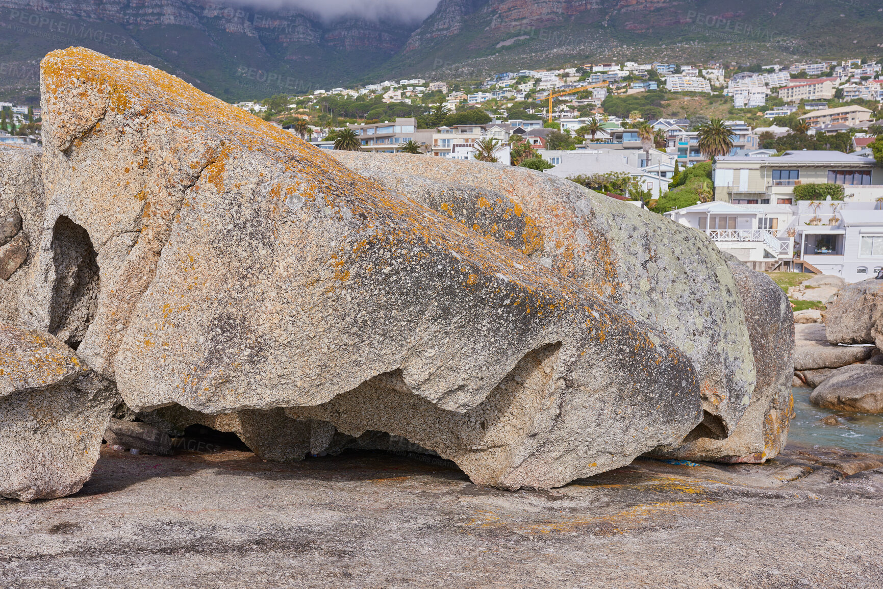 Buy stock photo Boulders on the rocky coast of Western Cape, South Africa, Landscape view of a beautiful mountain, houses, and hotels in Cape Town. Natural environment in a popular tourist location for a holiday