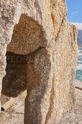 Buy stock photo Closeup of a crevice or gully formed by the erosion of sea water. Large boulder or sandstone on a beach with the ocean in the background. Sedimentary rock acting as wave breaker on coastal seaside