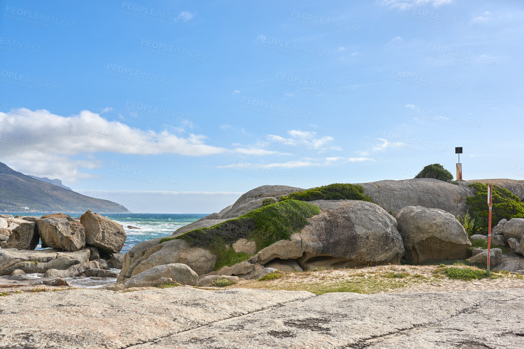 Buy stock photo Copy space, sea and ocean rocks on a remote, quiet and serene beach in a relaxing tropical coastal destination with a mountain background. Seascape, blue sky and tidal water on secluded island abroad