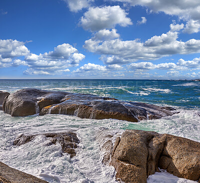 Buy stock photo Rocks in the ocean under a blue cloudy sky with copy space. Scenic landscape of beach waves washing over boulders or big stones in the sea at a popular summer location in Cape Town, South Africa