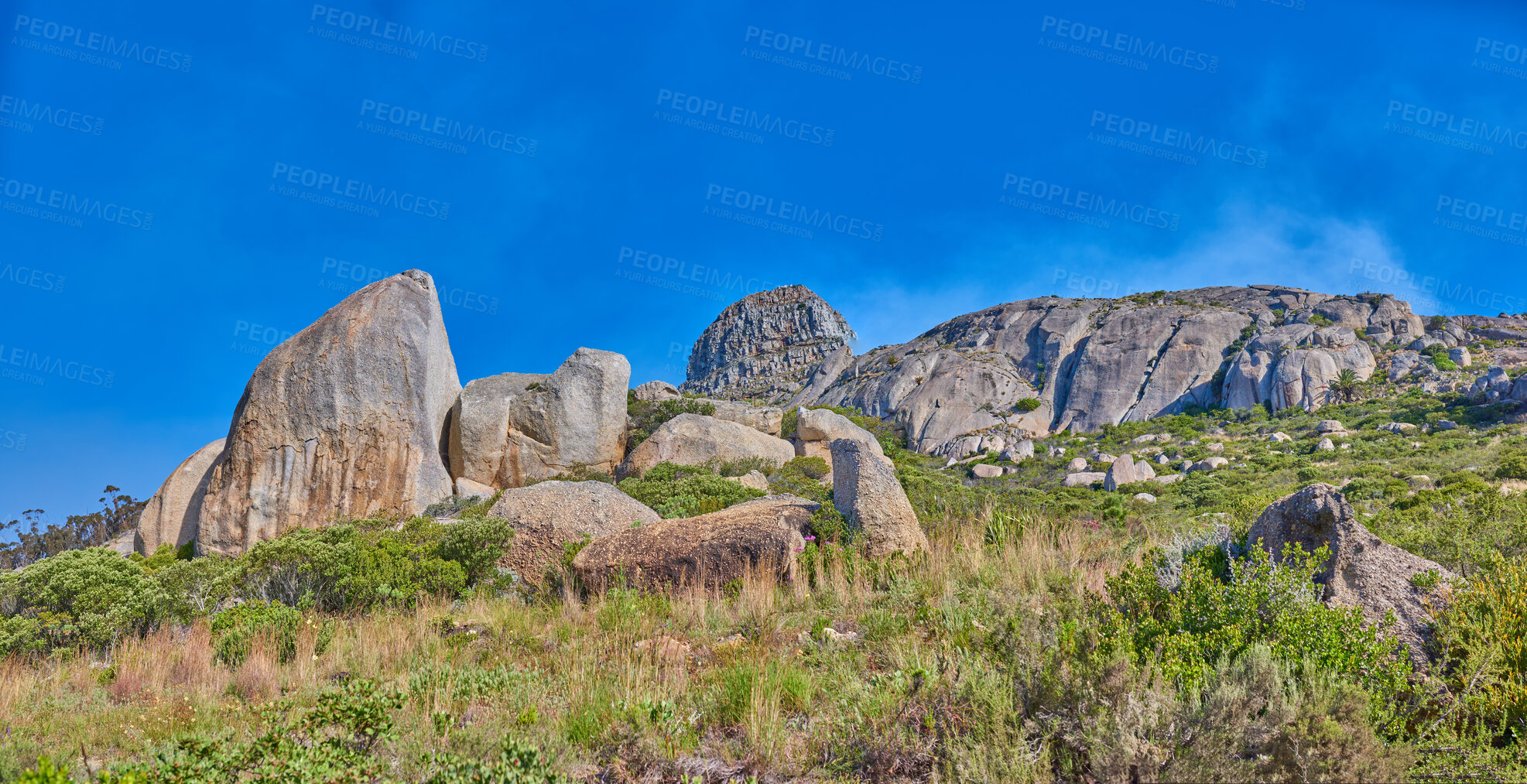 Buy stock photo Landscape of rocky mountain with boulders against a blue sky in summer. Green field with rocks and wild grass growing on sunny day outside with copy space. Scenic remote travel destination in nature