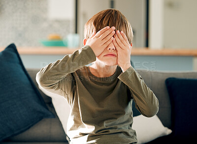 Buy stock photo Hide and seek or peekaboo with boy on sofa in living room of home, playing games for fun or leisure. Cover eyes, emoji and hands on face of kid in apartment for child development or counting