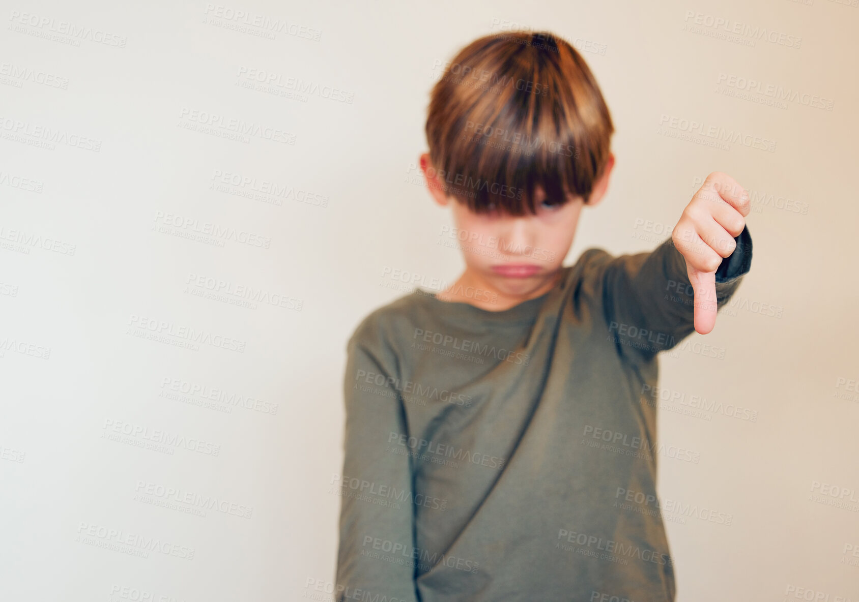 Buy stock photo Boy, studio and portrait with thumbs down for disagree or opinion, no vote or review for adhd. Kid, white background and hand emoji for autism feedback or protest with fail, serious or sad with sign