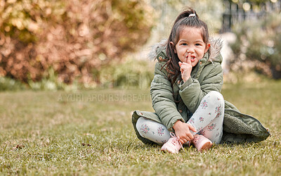 Buy stock photo Shot of an adorable little girl holding her finger over her mouth while sitting outside